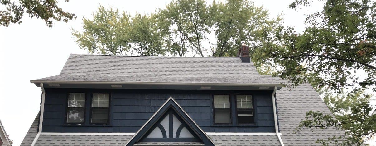 Tudor-style home after painting, with navy shake siding and white trim