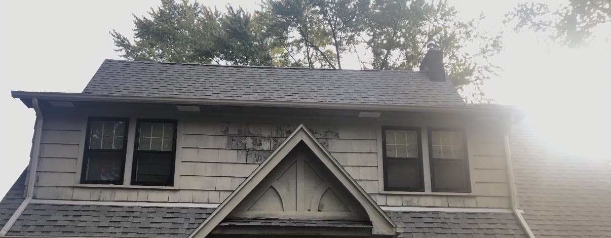 Tudor-style home before painting, with faded gray shake siding