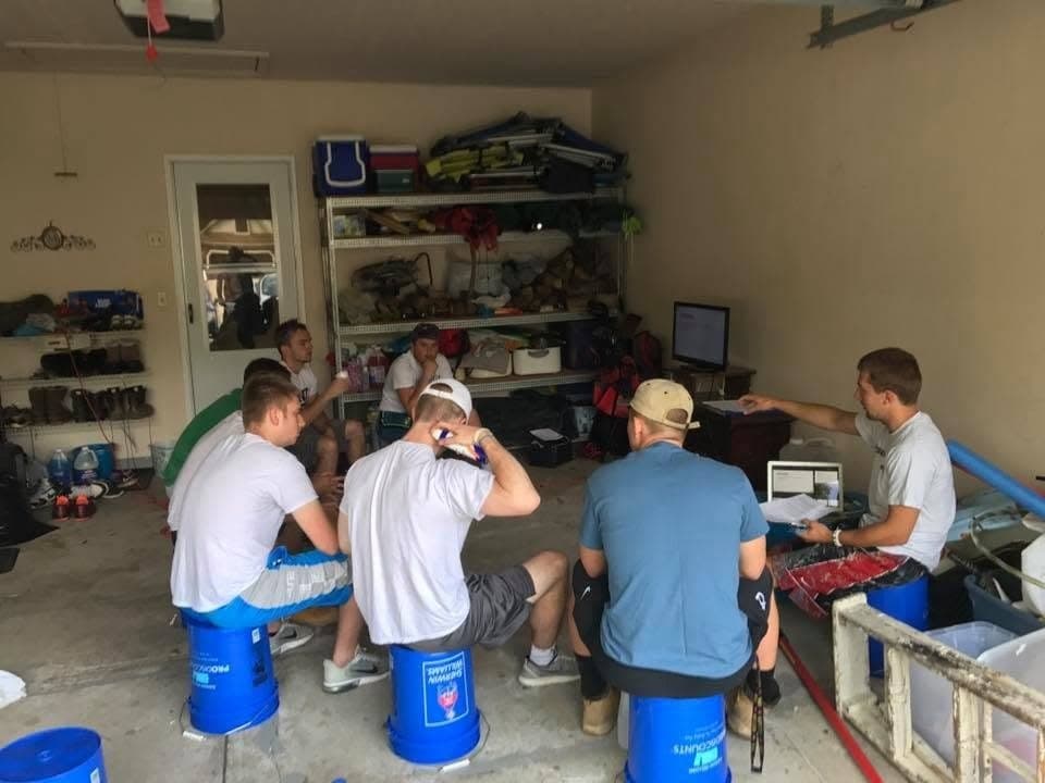 The Wildwood crew in 2015, seated on Sherwin-Williams paint buckets in a garage for a crew meeting