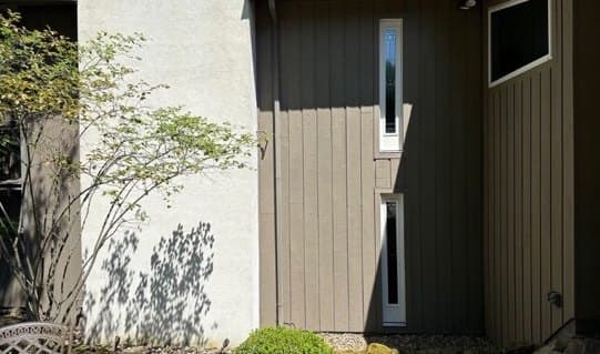 Tall side wall refinished in taupe beside a white stucco section, after