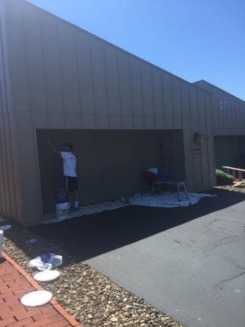 Painter working inside a garage bay with drop cloths spread across the driveway