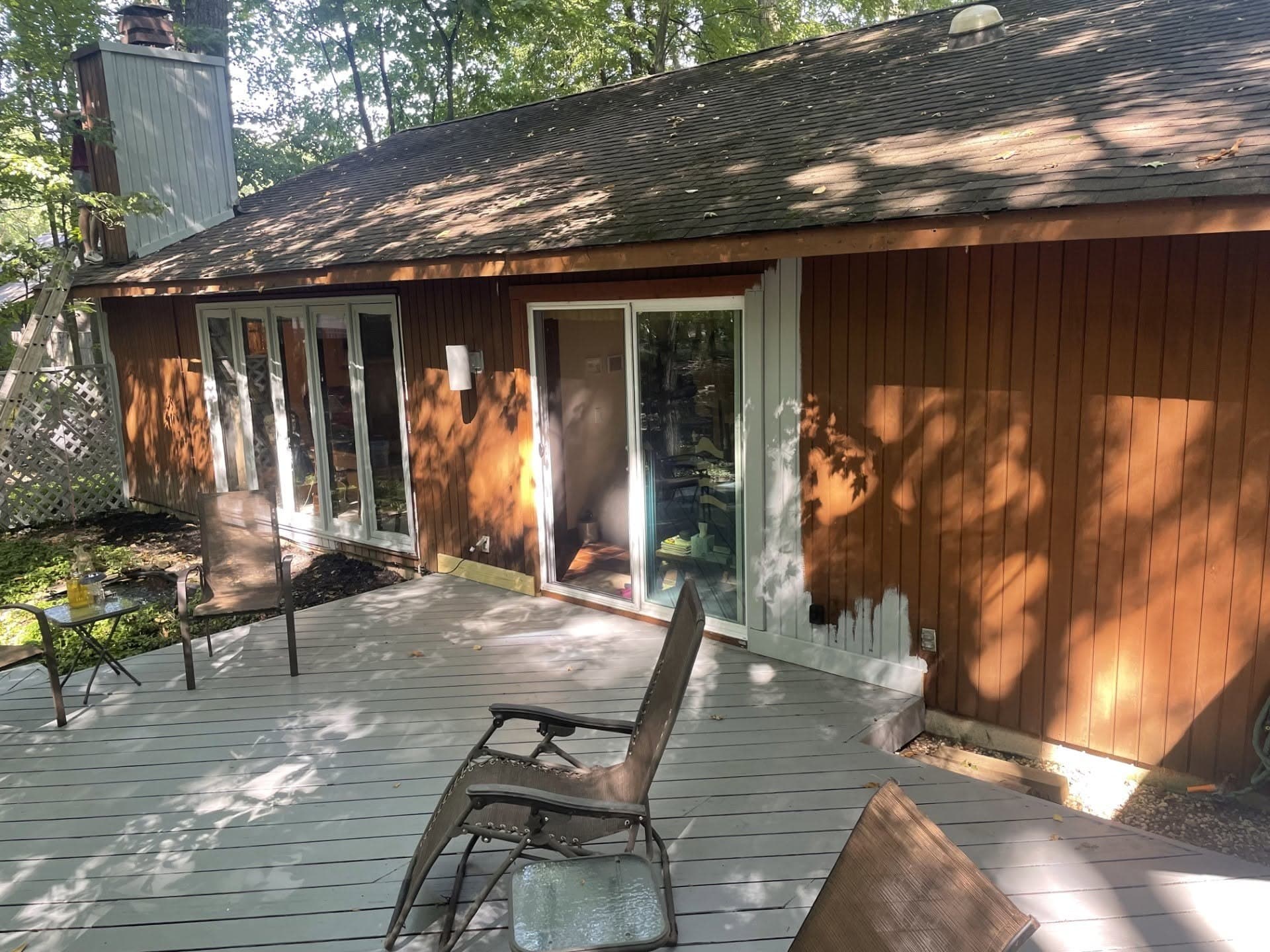 Wood siding nearly finished in white with the original brown still showing at the far end