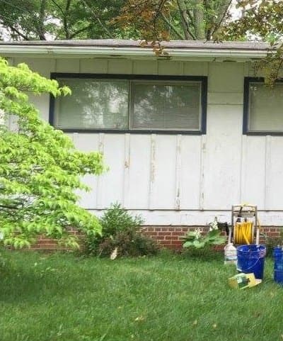 Front of the ranch home with worn white siding, before