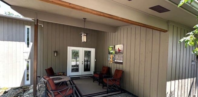Covered entry with warm taupe vertical wood siding after refinishing