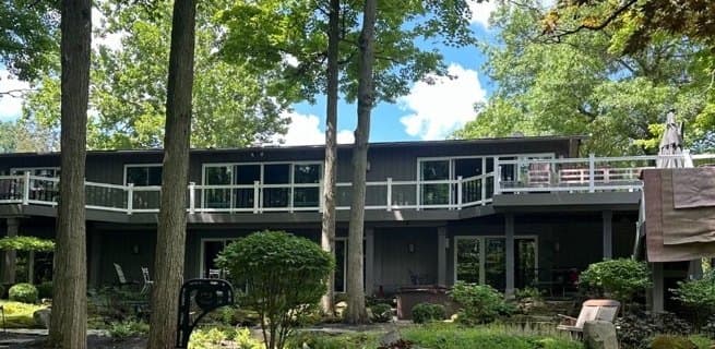 Rear of the home with dark siding and a long deck, before