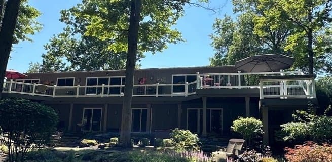 Rear of a contemporary wood-sided home with a long elevated deck after the siding was refinished